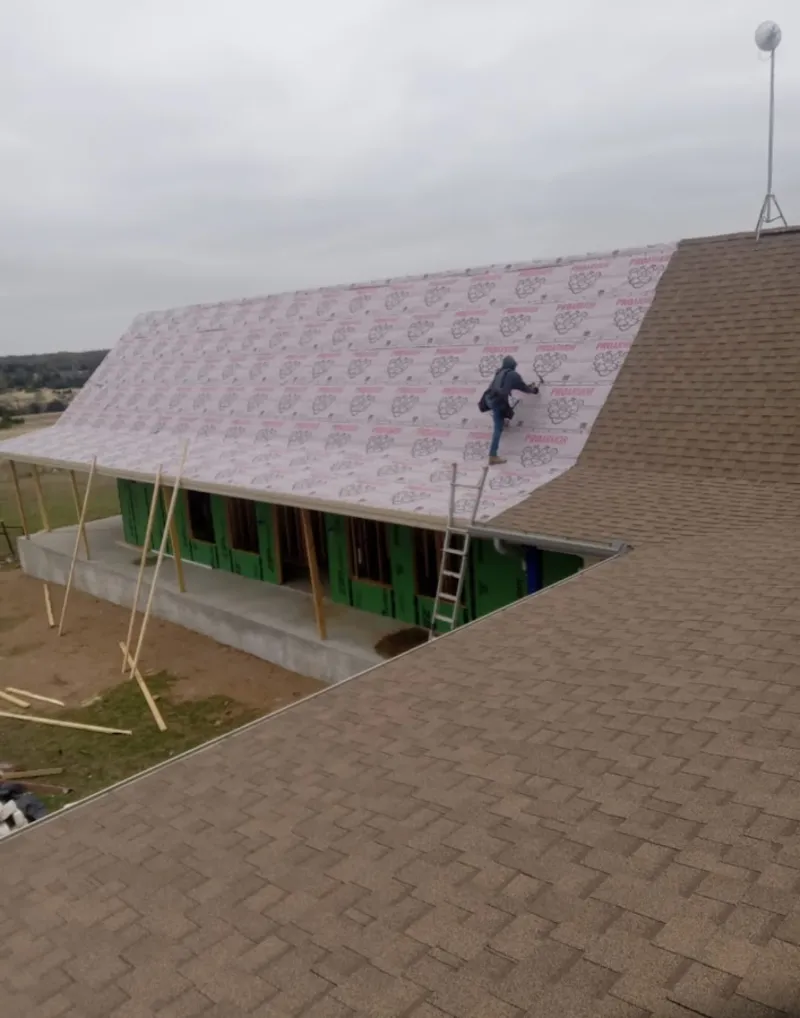 Worker preparing underlayment for a metal roof installation in Bath